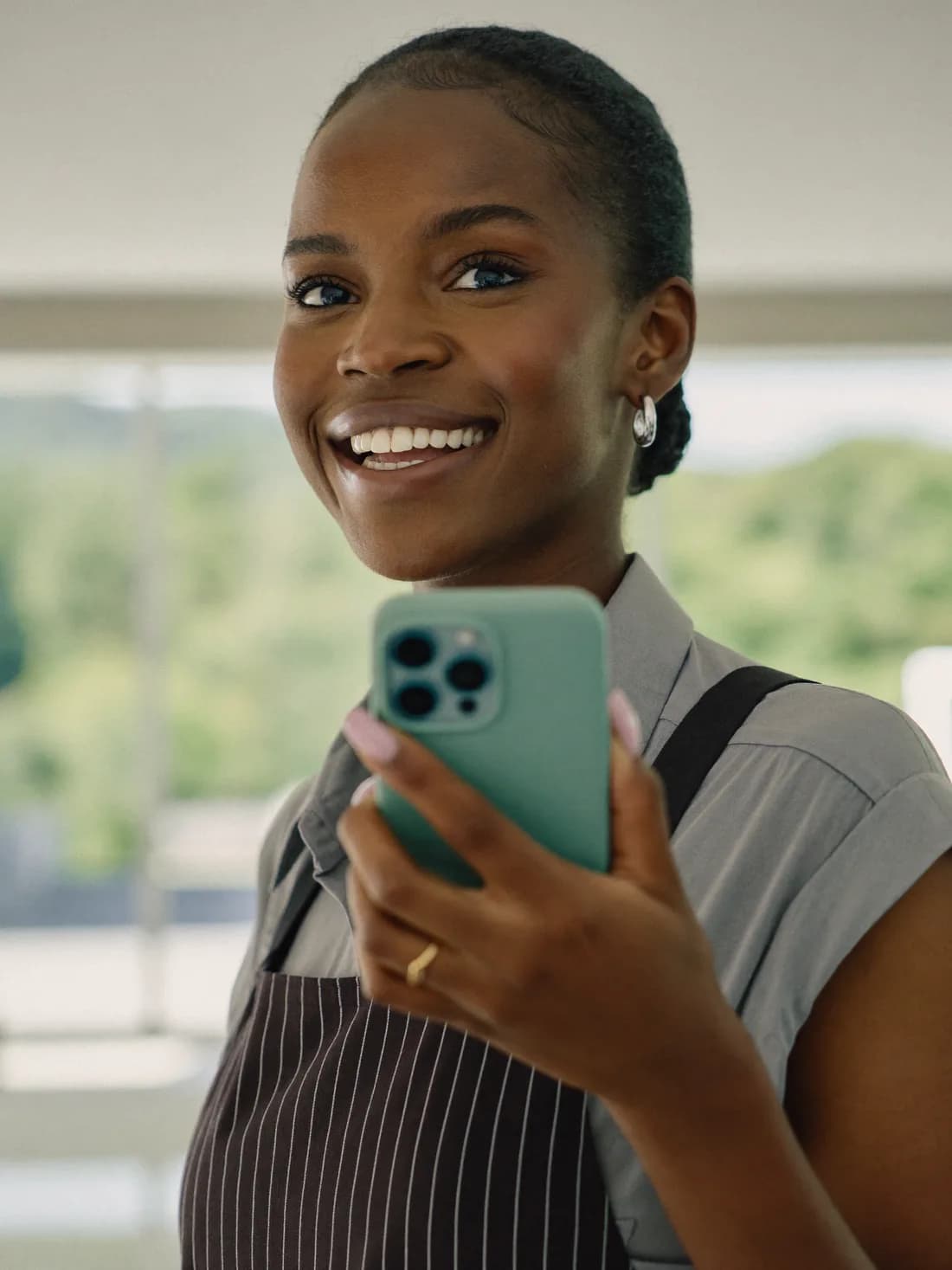 An Edubaze partner smiling, holding her phone after signing up a school